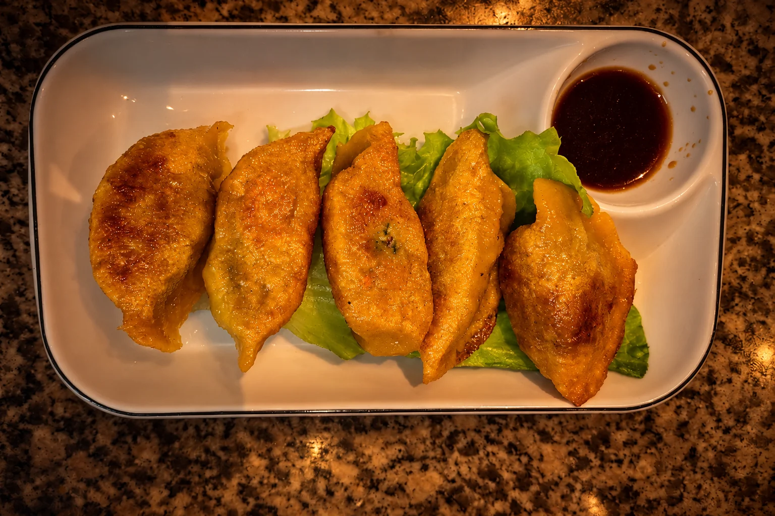 Chicken dumplings on lettuce, white rectangular plate, warm evening light