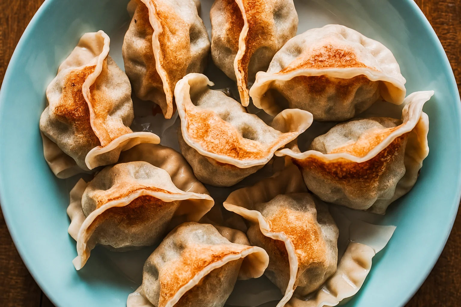 Pan-fried dumplings in a light blue plate, wooden table